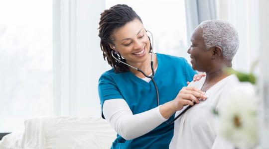 Young Black doctor attends to elderly Black woman