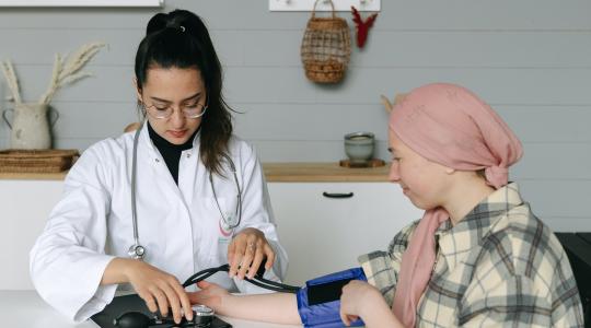 Young woman doctor checking patients blood pressure